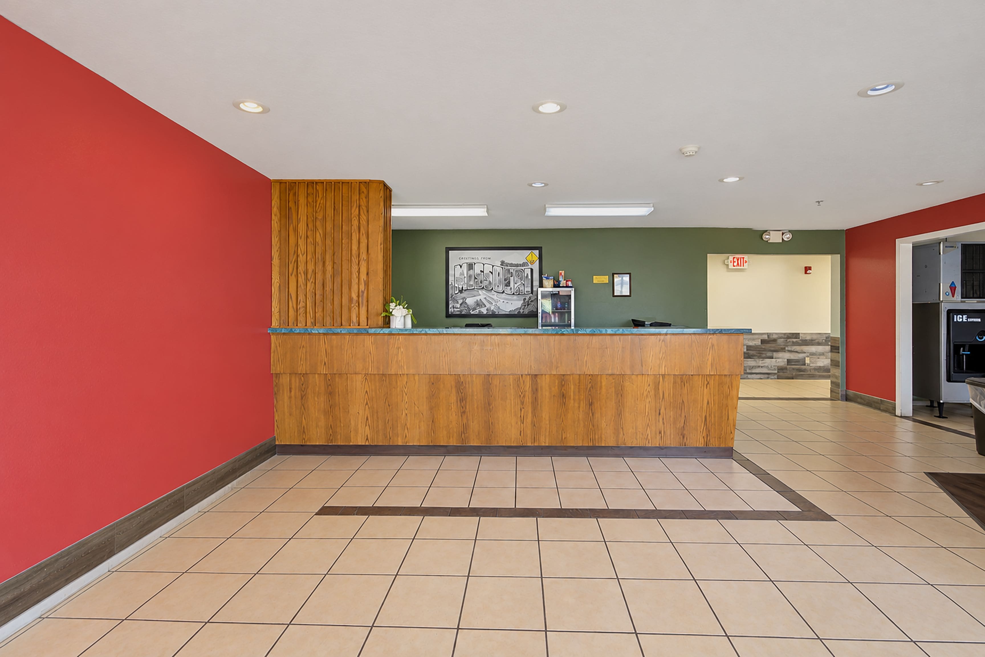 A reception area with a wooden counter, a framed picture on the wall, and a tiled floor.