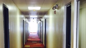 A long, narrow hallway with tiled floors and a red carpet. - Texas Inn & Suites (Lufkin)