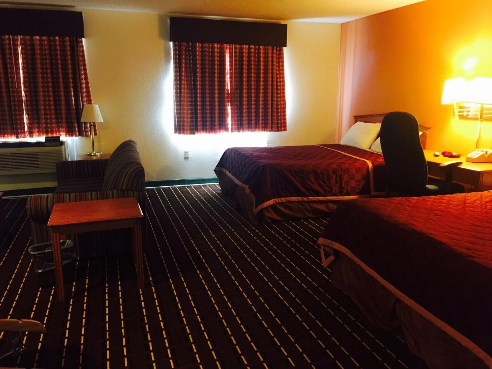 Una habitación de hotel con dos camas, un escritorio, una silla y una lámpara.