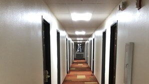 A hotel hallway with carpeted floors, doors on both sides, and a light fixture on the ceiling. - Texas Inn & Suites (Lufkin)