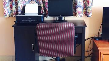 A home office setup with a computer, monitor, printer, and striped office chair.
