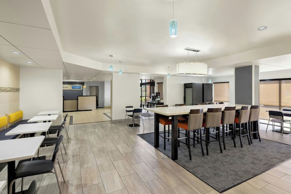 A modern hotel lobby with a reception desk, seating area, and a bar.