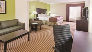 Quarto de hotel com cama, sofá, escrivaninha, cadeira e televisão.