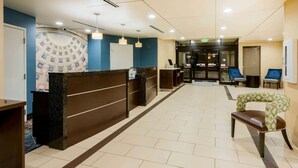 Uma área de recepção de hotel com balcão de mármore, paredes azuis e teto estampado.