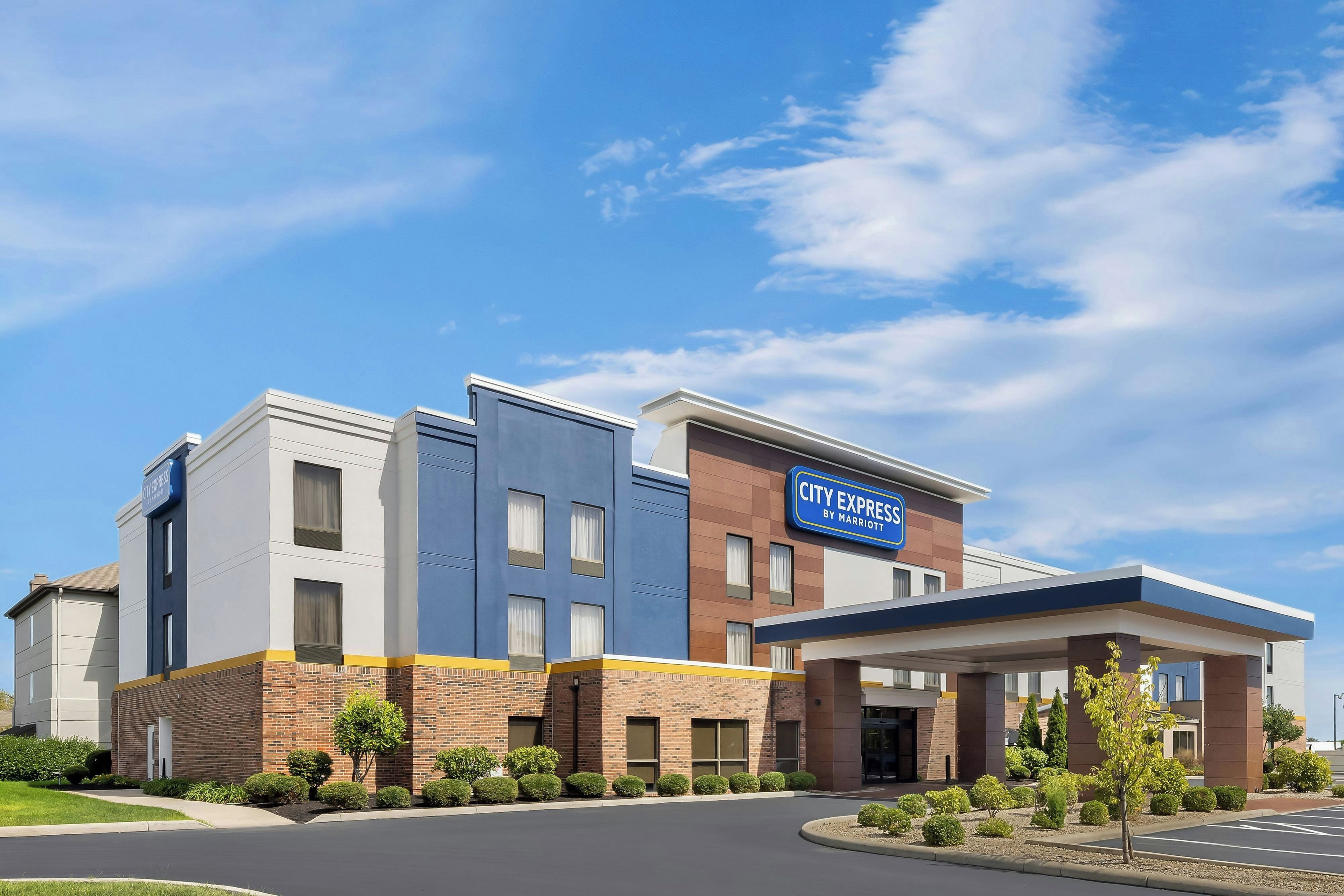 Hotel City Express by Marriott, com design moderno, fachada de tijolos e esquema de cores azul e branco.