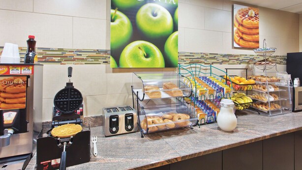 Um buffet de café da manhã com diversos alimentos e uma máquina de waffles.