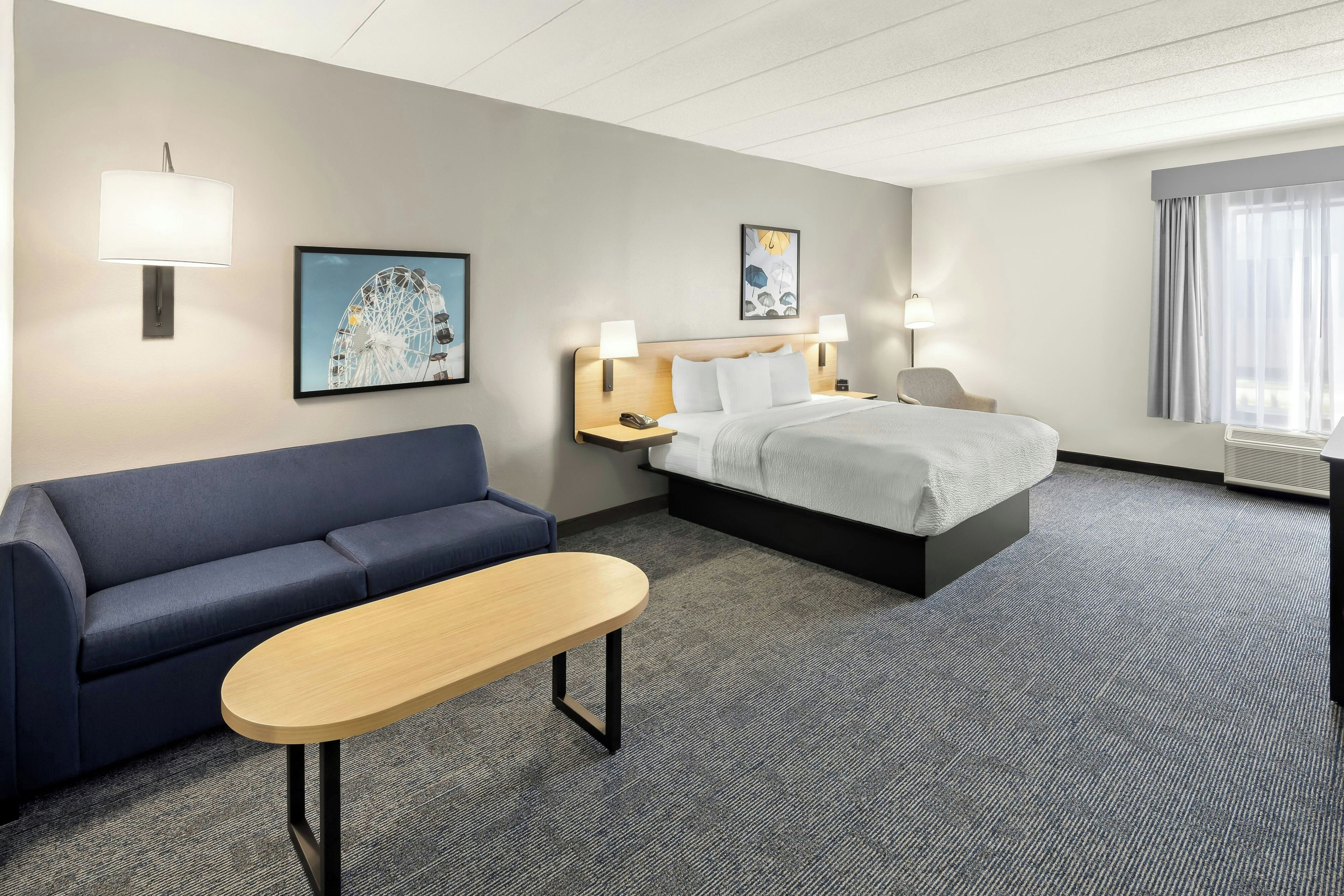 Ein Hotelzimmer mit einem Bett, einem Schlafsofa, einem kleinen Tisch und zwei Wandlampen.