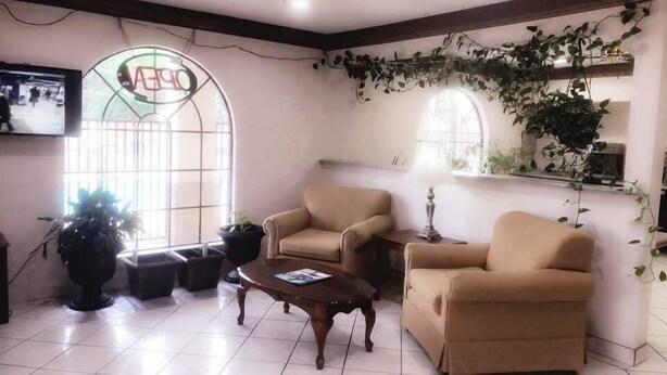 A cozy living room with two beige armchairs, a wooden coffee table, and a large window with a view. - Majestic Inn (Longview)