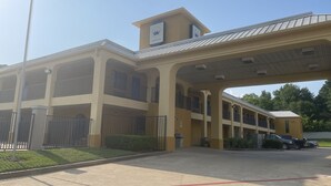 A multi-story hotel with a central atrium, balconies, and a parking area. - Majestic Inn (Longview)
