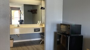 A modern kitchen with a microwave on top of a refrigerator, a sink, and a countertop. - Majestic Inn (Longview)