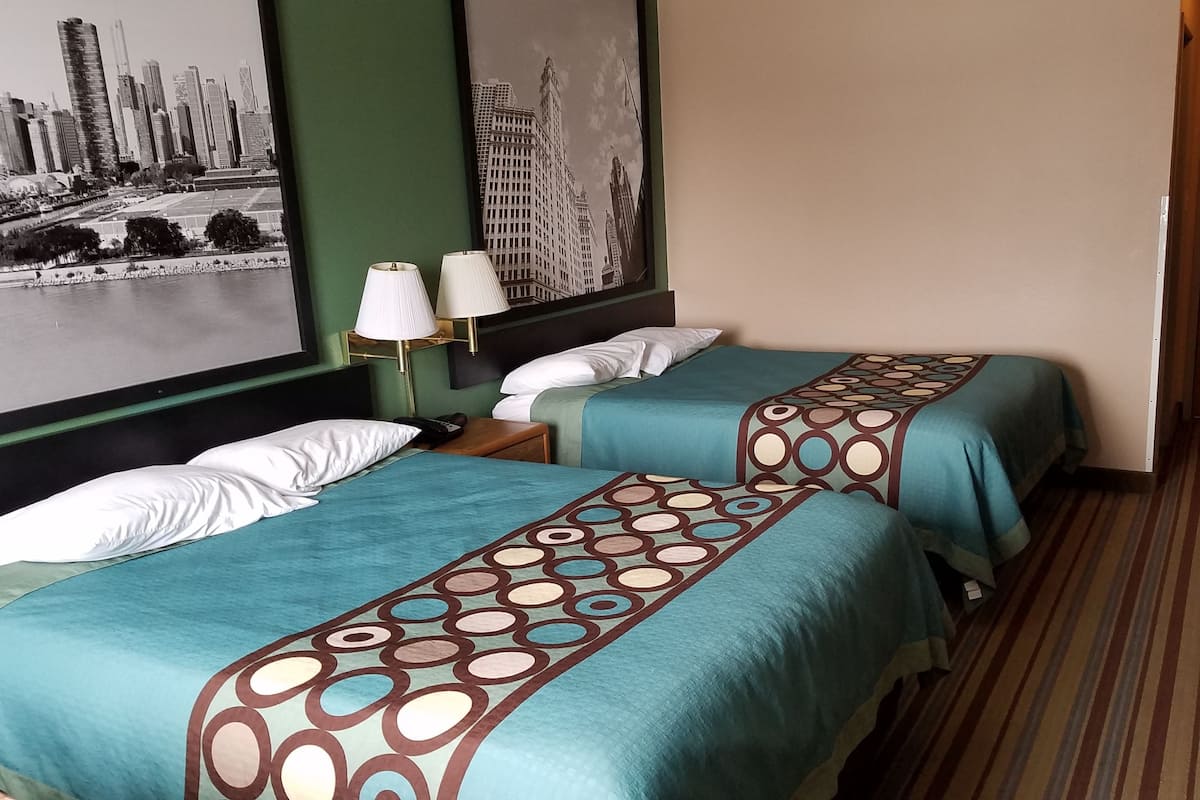 A hotel room with two beds, a cityscape mural, a green wall, and a striped carpet.