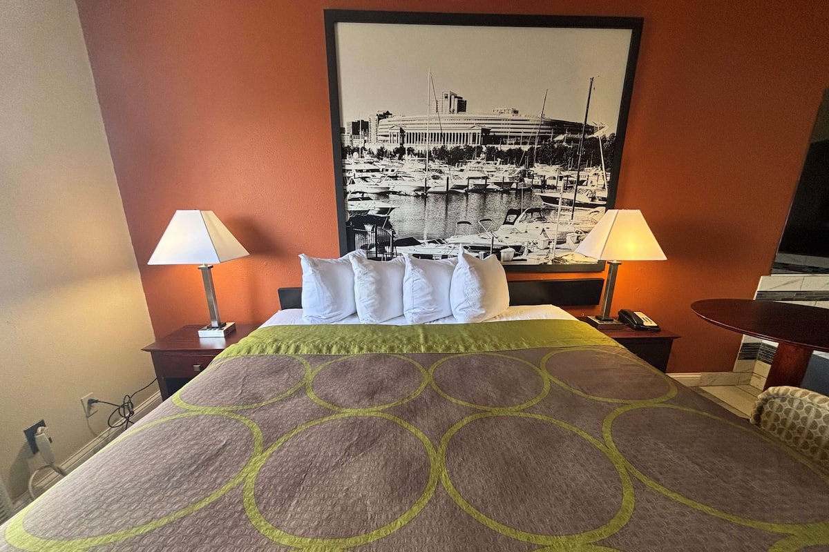 A hotel room with a bed, two bedside lamps, a nightstand, a desk, and a chair.