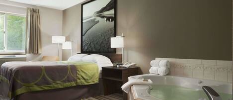 A hotel room with a bed, a large window, a bathroom with a bathtub, and a framed picture on the wall.
