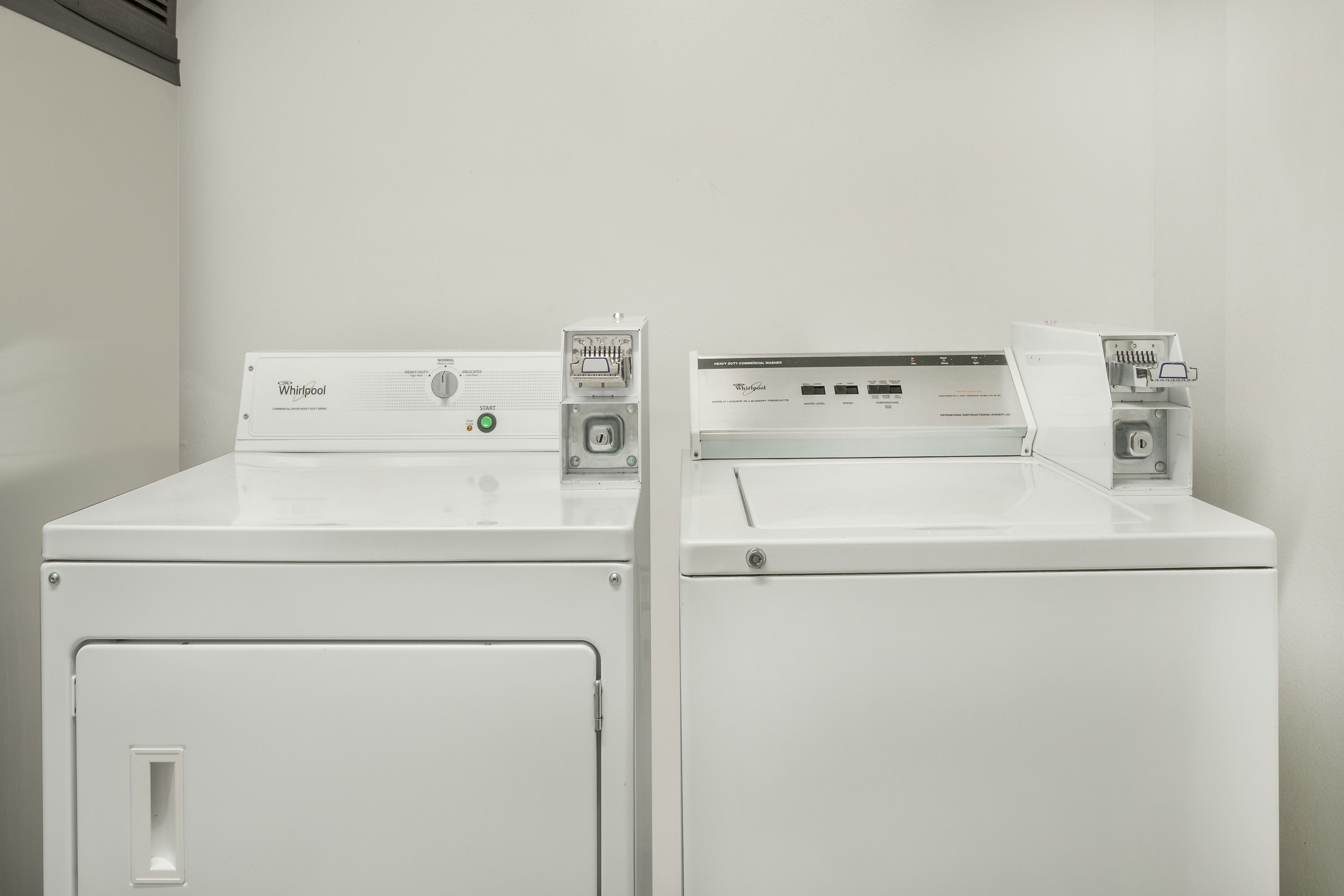 Dos lavadoras Whirlpool blancas de carga frontal una al lado de la otra en una habitación con paredes blancas.