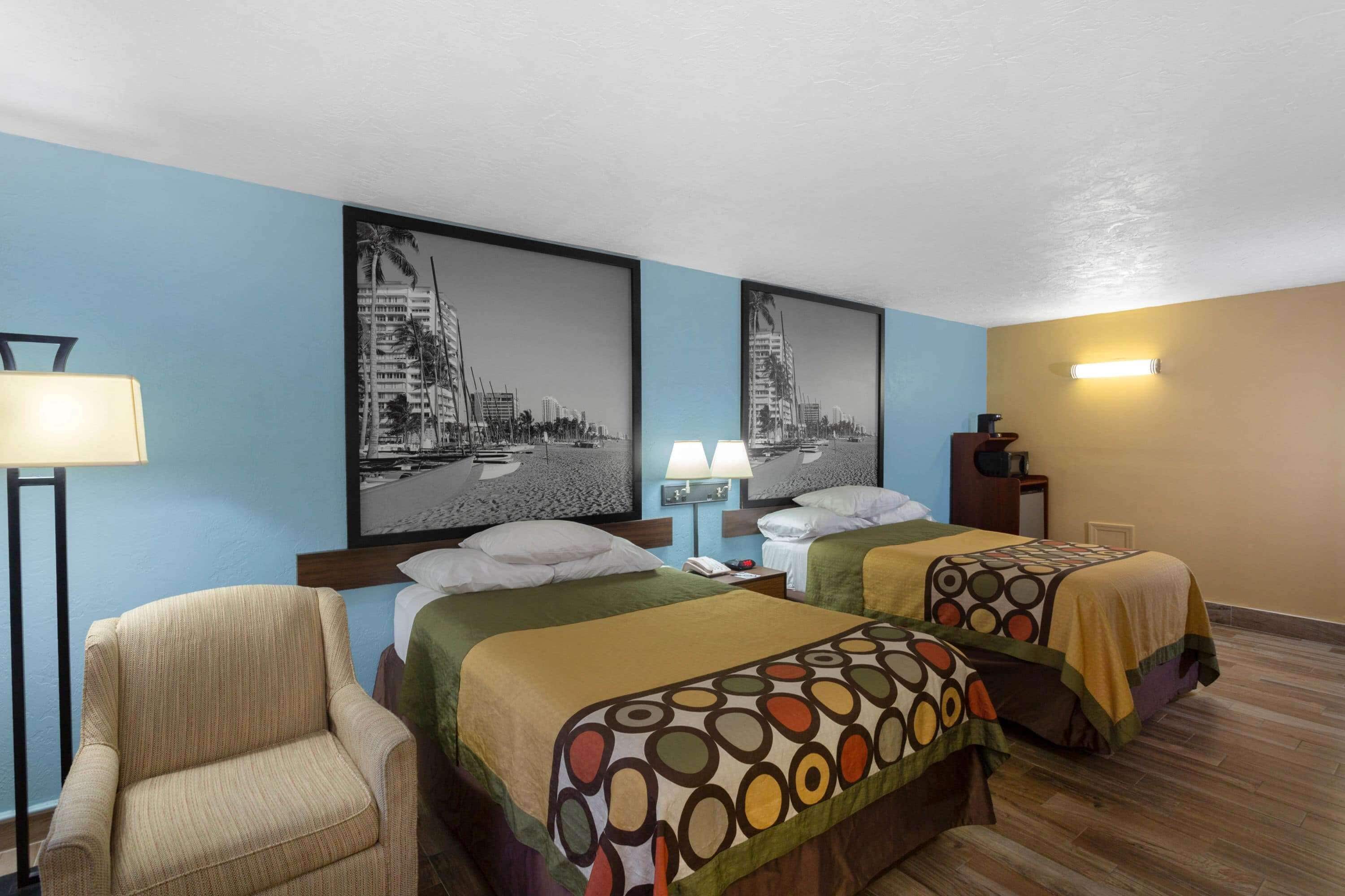 A hotel room with two beds, a chair, and a desk.