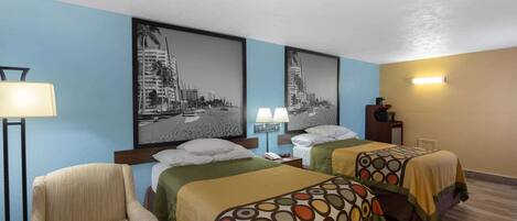 A hotel room with two beds, a chair, and a desk.