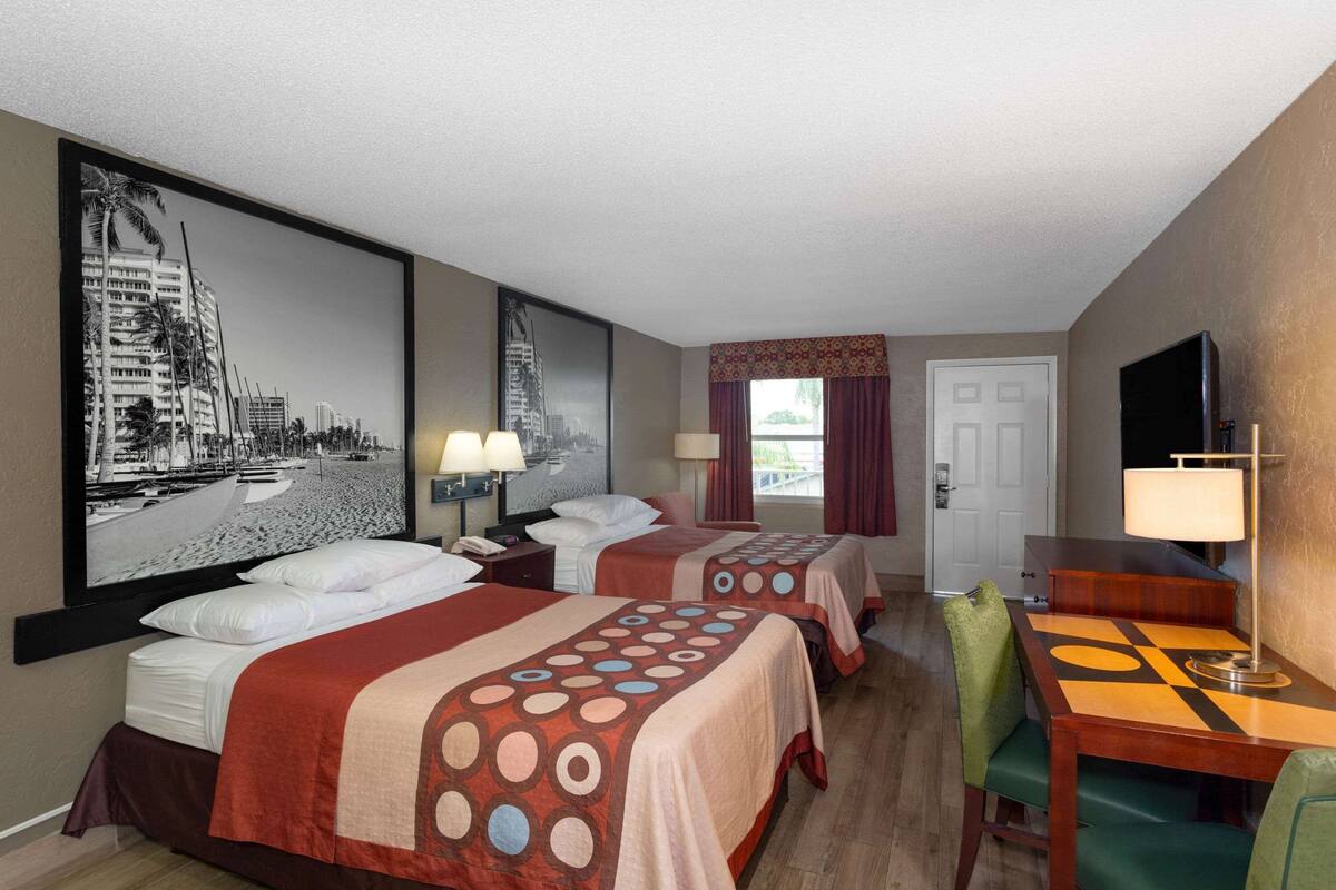 A hotel room with two beds, a dining table, and a TV.