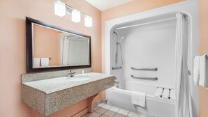 A bathroom with a granite sink, a large mirror, a shower with a curtain, and a white bathtub.