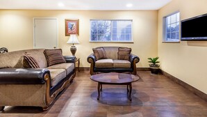 A living room with two sofas, a coffee table, a lamp, and a TV mounted on the wall.