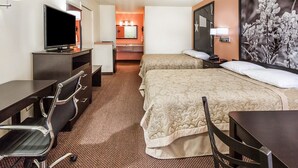 A hotel room with a TV, desk, chairs, a bed, and a bathroom visible in the background.
