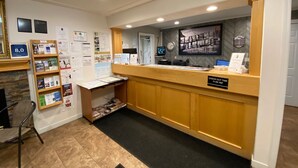 A reception desk with informational brochures, a clock, and a sign indicating check-out times.