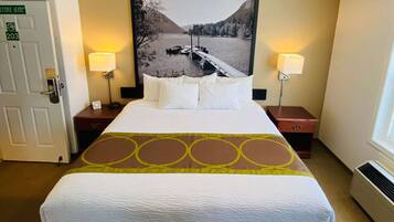 Une chambre d’hôtel avec un lit, deux lampes de chevet, une table de nuit, un tableau représentant un lac et une porte portant l’inscription « Suite de direction 203 ».