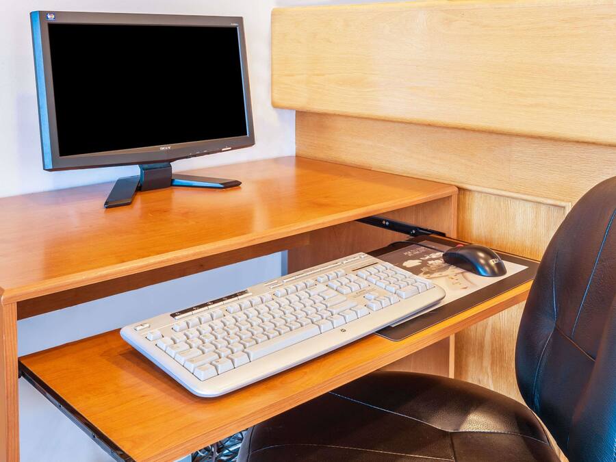 A wooden desk with a computer monitor, keyboard, and mouse.