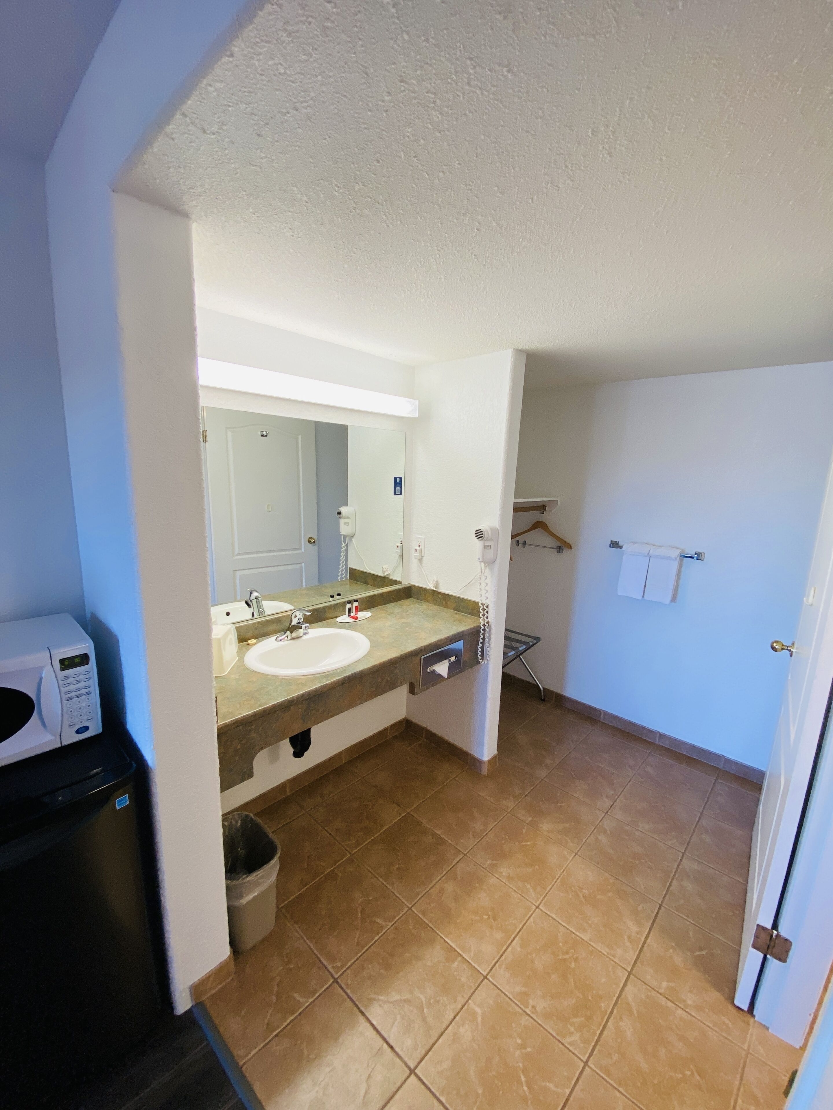A bathroom with two sinks, a mirror, a towel rack, and a microwave.