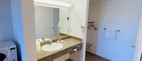 A bathroom with two sinks, a mirror, a towel rack, and a microwave.