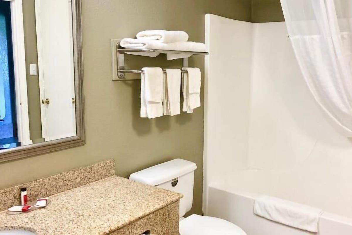A bathroom with a toilet, sink, and shower. There are towels on a rack and a shower curtain.