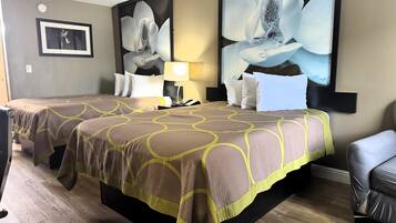 Habitación de hotel con dos camas, una mesita de noche, una lámpara y un cuadro grande con flores en la pared.