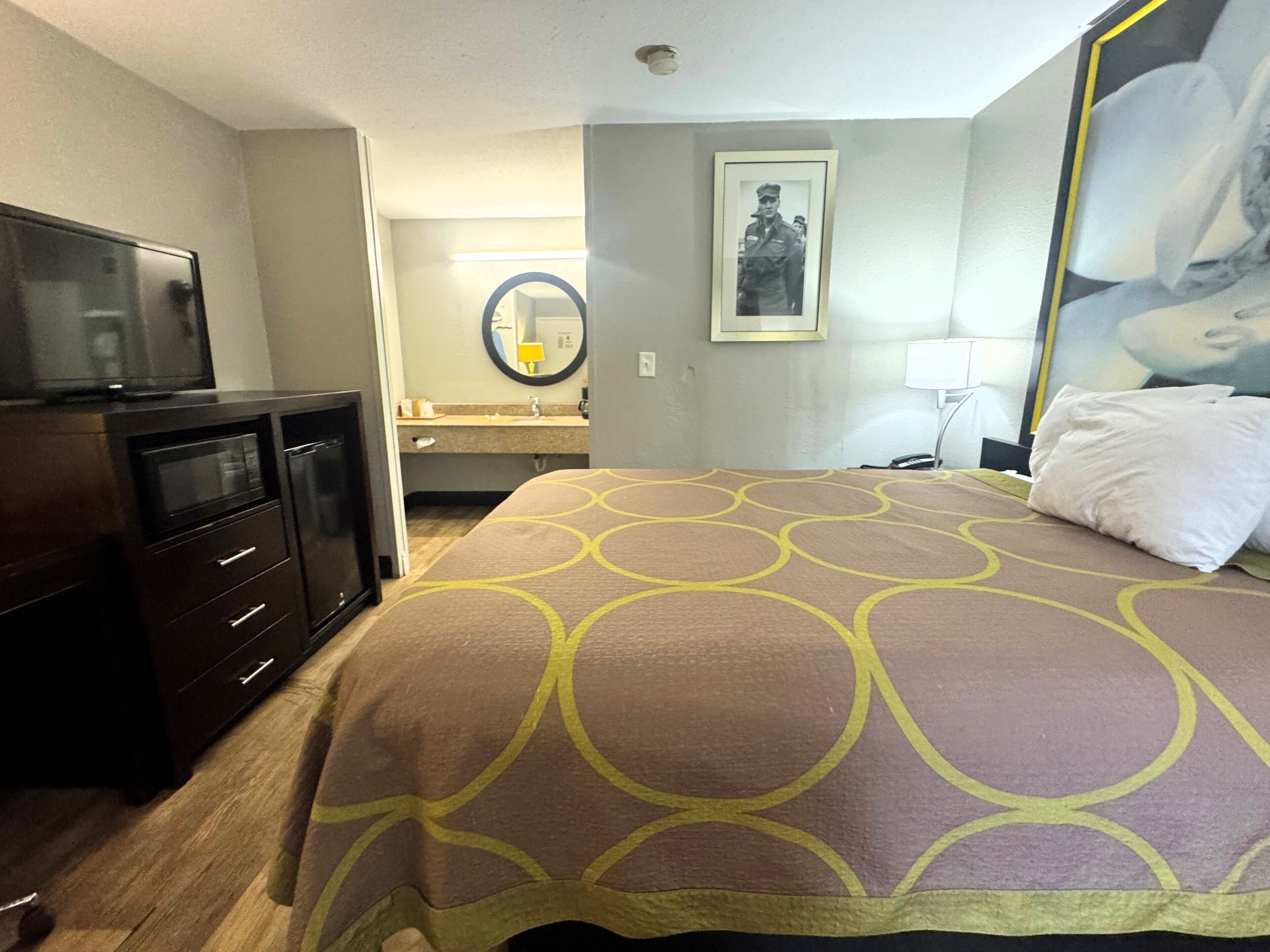 Una habitación de hotel con una cama, televisión, escritorio y baño al fondo.