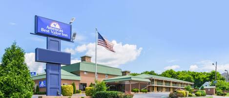 A Best Value Inn with a large sign, a flag, and a building with a green roof.