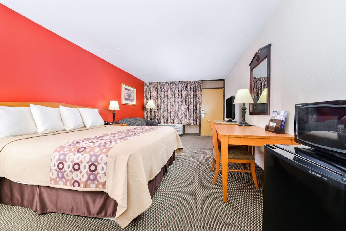 A hotel room with a bed, a desk, a television, and a bathroom.