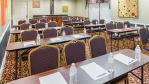 A conference room with rows of tables and chairs, equipped with water bottles and pens. - Americas Best Value Inn Goodlettsville Nashville N (Goodlettsville)