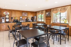 A breakfast area with wooden paneling, a coffee machine, and a counter with various appliances. - Super 8 by Wyndham League City/Kemah Area (League City)