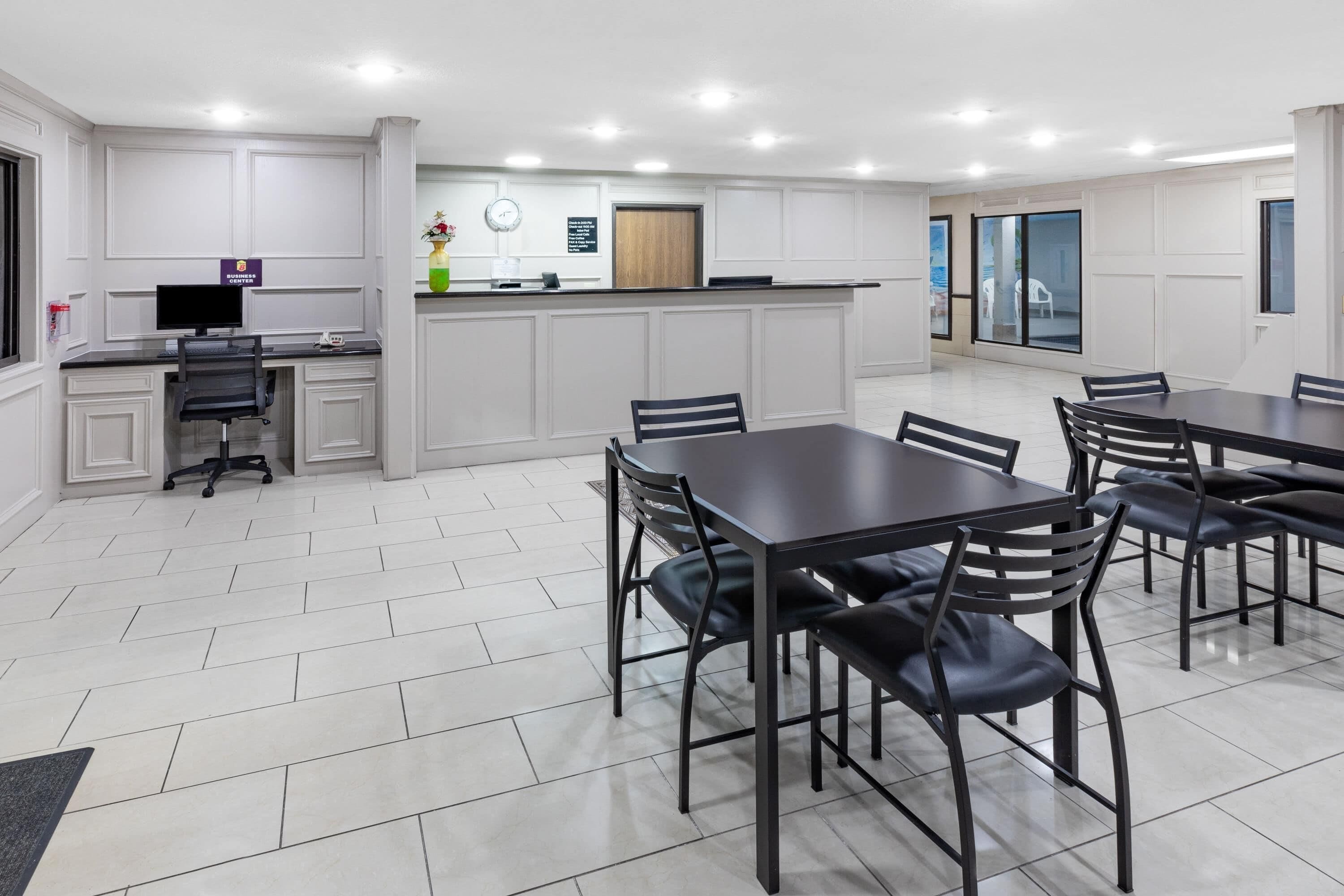 A modern hotel room with a dining area, a reception desk, and a view of the outside.