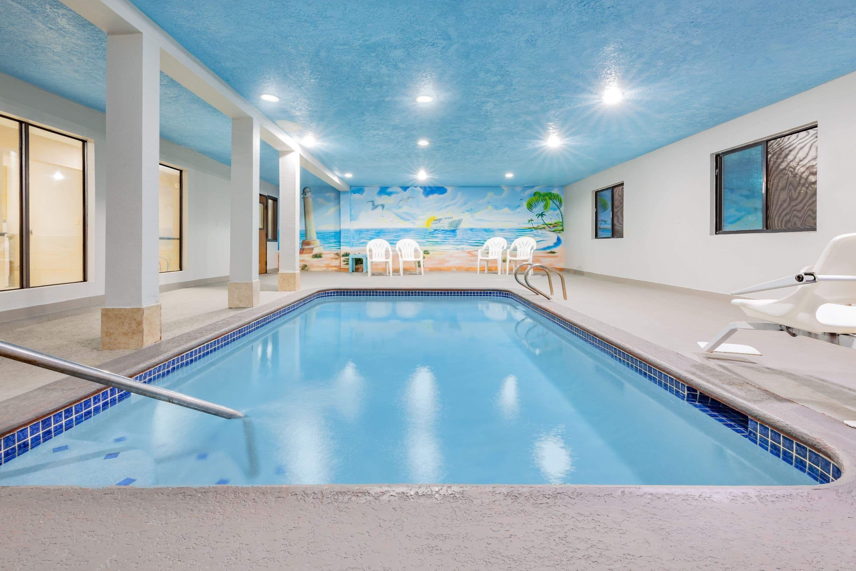 An indoor swimming pool with a mural of a beach scene on the walls.