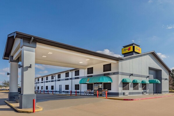 Un hotel con una gasolinera adjunta, con un toldo grande sobre la entrada y varios ventanales.