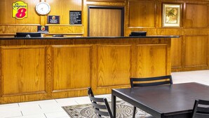 A hotel reception area with a wooden reception desk, a clock, and a framed picture on the wall.