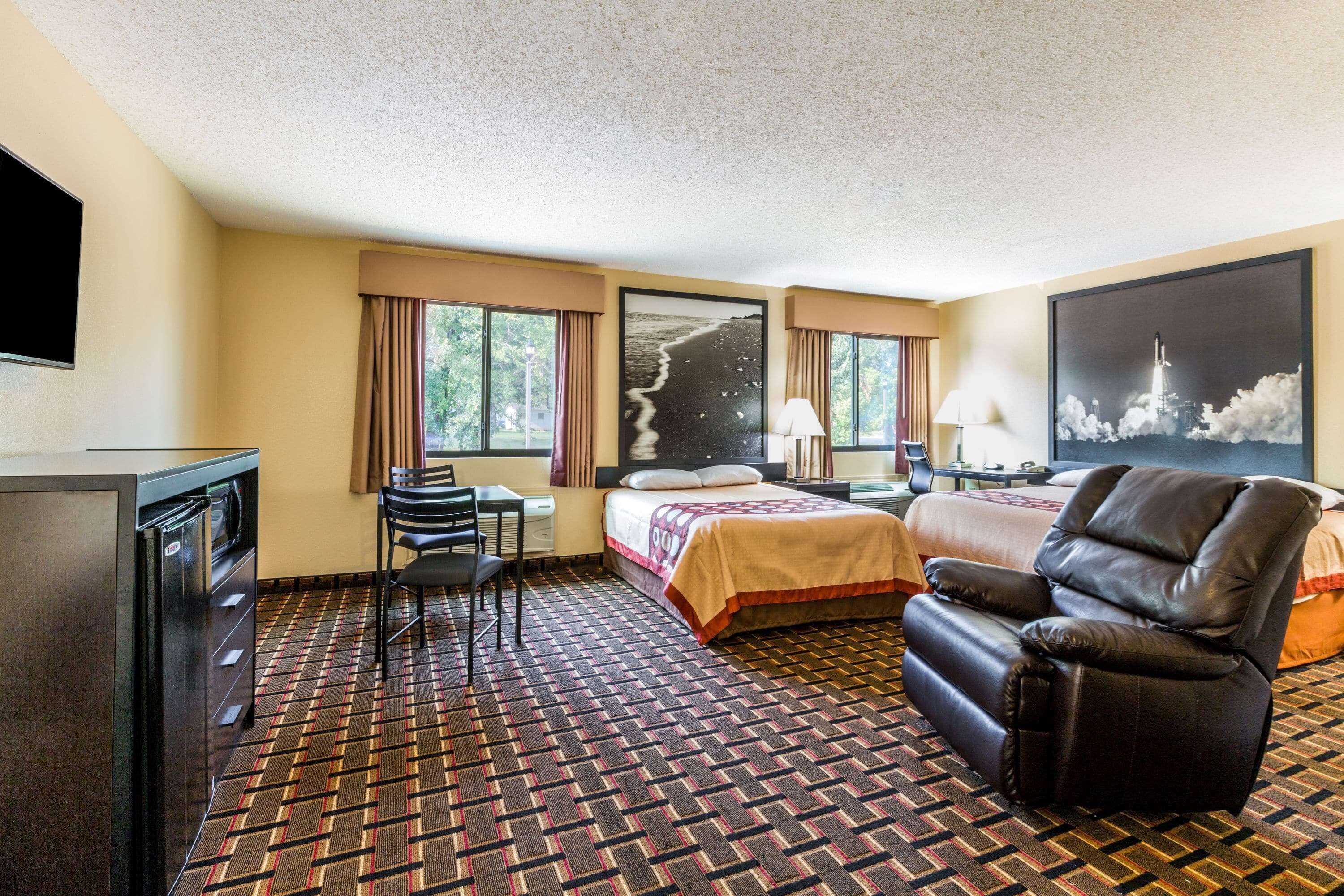 A hotel room with a bed, a desk, a chair, a TV, and a window with curtains.