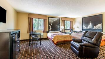 A hotel room with a bed, a desk, a chair, a TV, and a window with curtains.