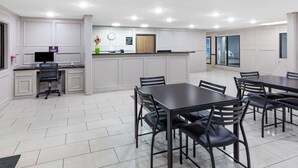 A modern hotel room with a dining area, a kitchen, and a reception desk.