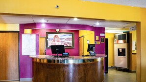 A reception desk with a computer, a clock, and a framed picture of a bridge.