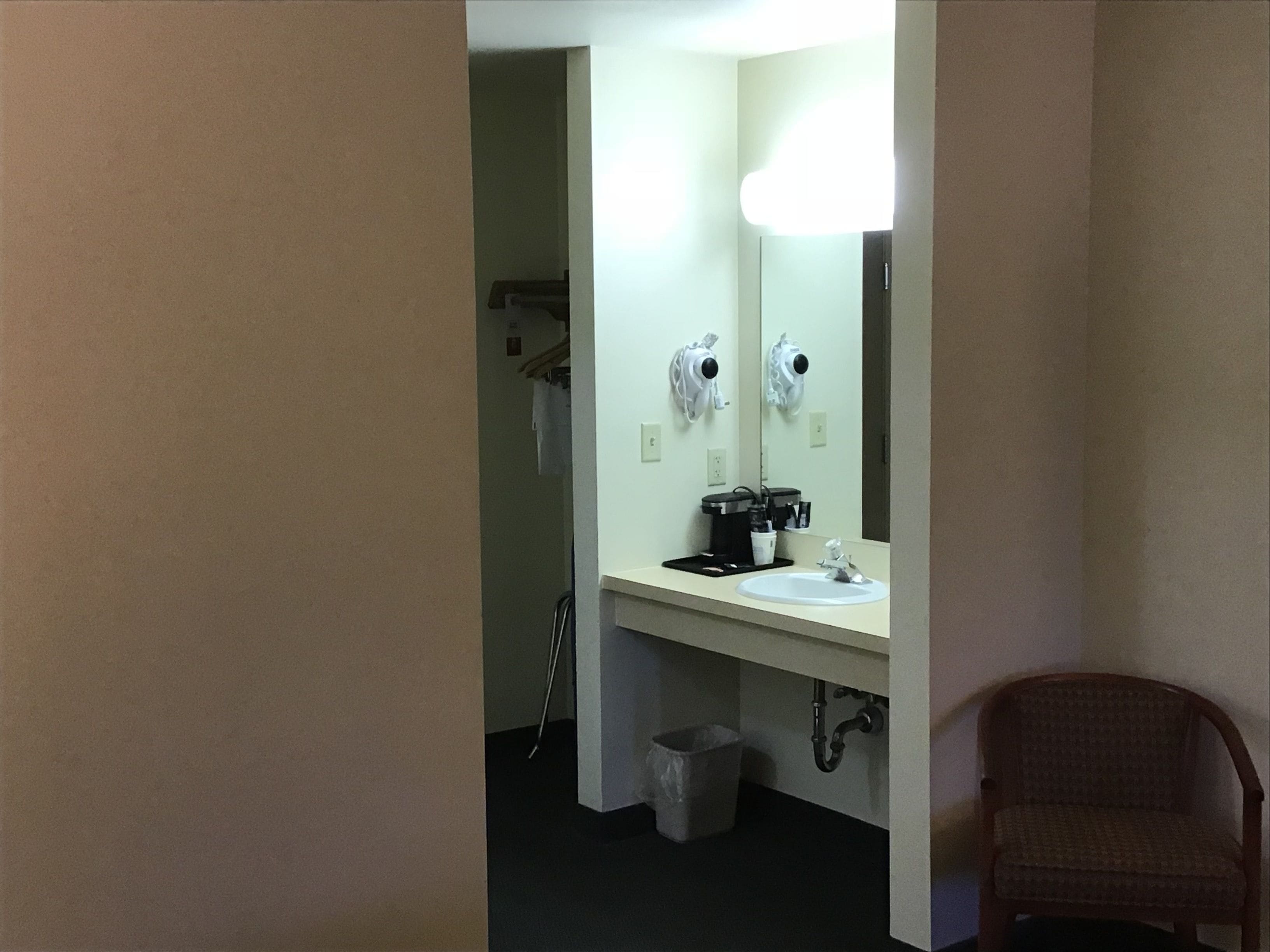 Une salle de bain d’hôtel équipée d’un lavabo, d’un miroir, d’un sèche-cheveux et d’une poubelle.
