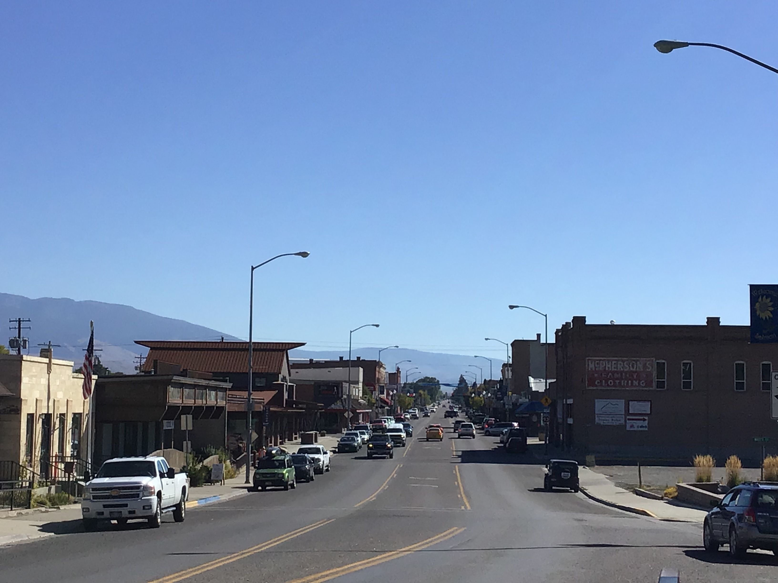 Vista de la calle con edificios, coches y una montaña al fondo.