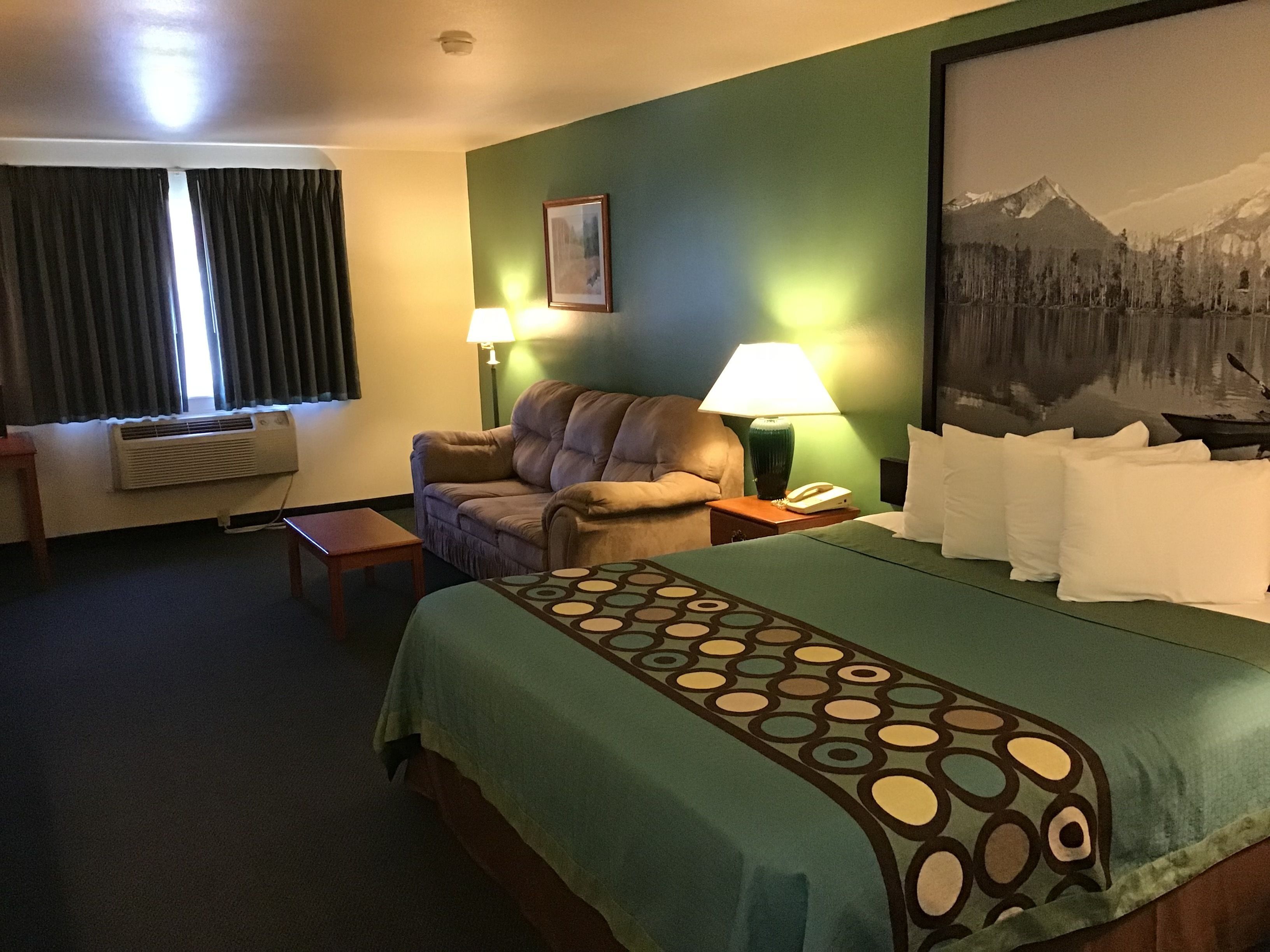 Een hotelkamer met een bed, een slaapbank, een bureau en een lamp.