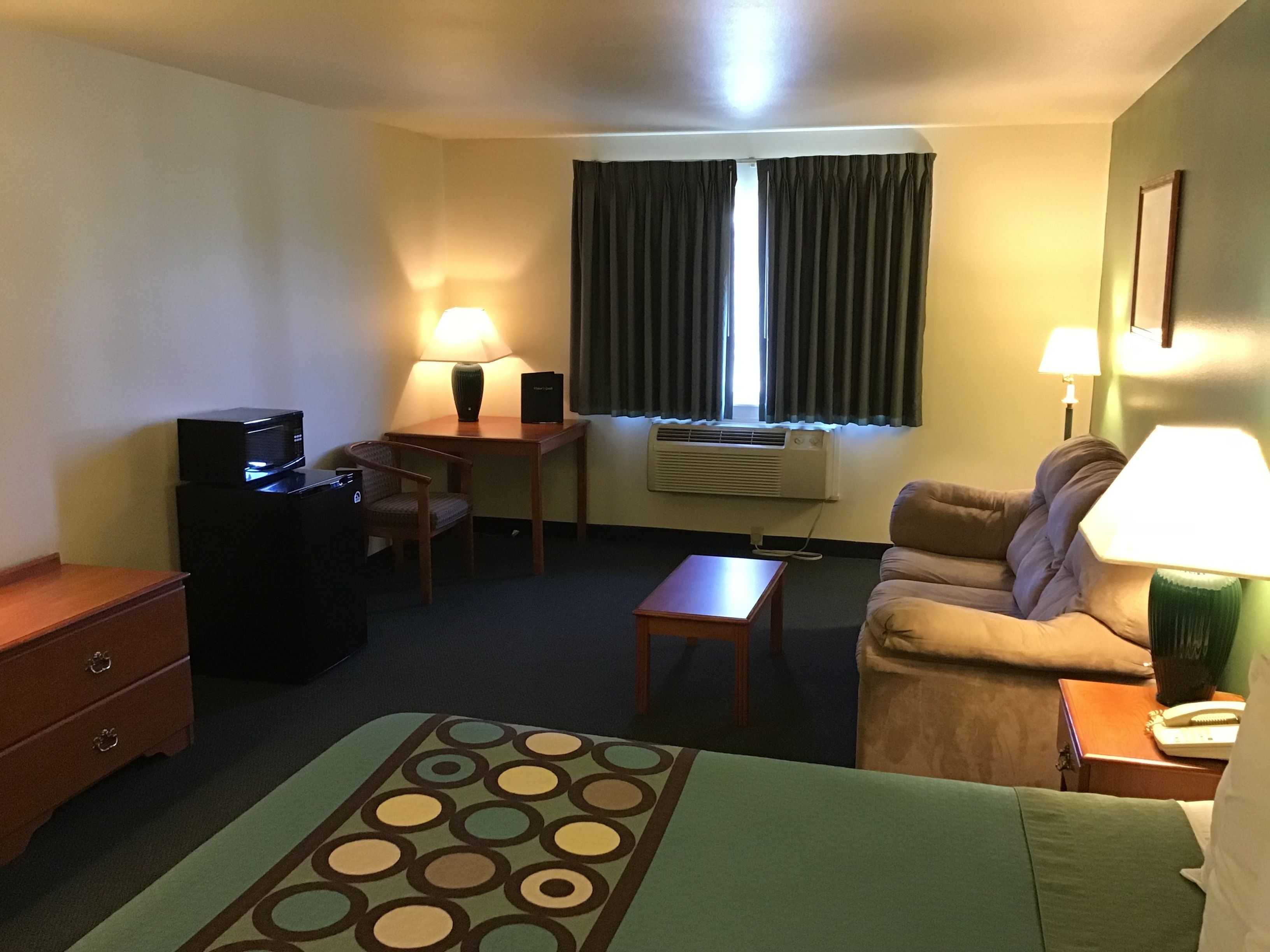 Une chambre d’hôtel équipée d’un lit, d’un bureau, d’une chaise, d’un canapé, d’une télévision et d’une lampe.