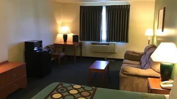 Une chambre d’hôtel équipée d’un lit, d’un bureau, d’une chaise, d’un canapé, d’une télévision et d’une lampe.