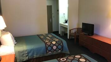 A hotel room with two beds, a desk with a chair, a television, and a dresser.
